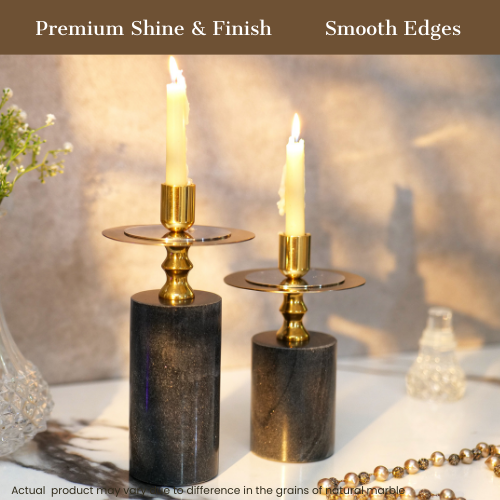 Elegant black and gold candlestick holders with lit candles on a wooden table.