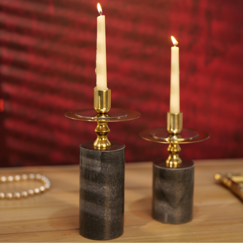 Elegant black and gold candlestick holders with lit candles on a wooden table.